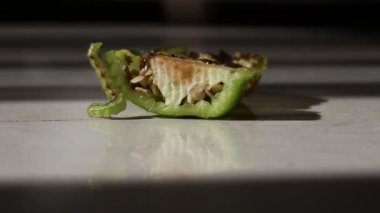 Yeşil tırtıl, beyaz arka planda biber yiyor. Noctuidae, genellikle baykuş güvesi olarak bilinir.