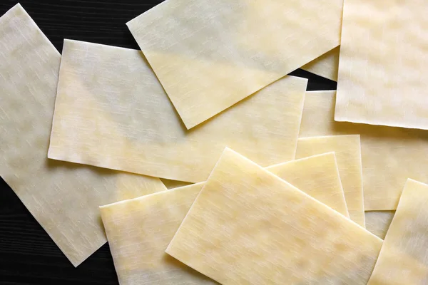 Dry lasagna pasta sheets on black textured wood from above. Abst — ストック写真