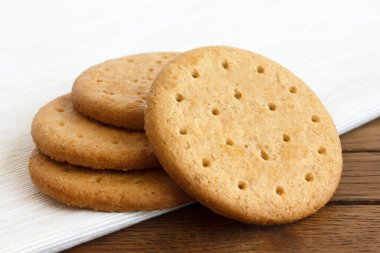 Stack of sweetmeal digestive biscuits on dark wood and napkin. clipart