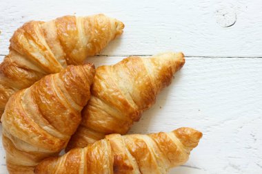 Yukarıdan rustik beyaz ahşap üzerinde Altın kruvasan.