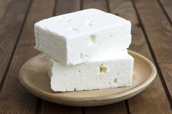 Bloque de queso feta griego en plato rústico y mesa . —  Fotos de Stock