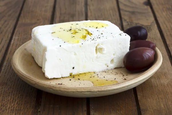 Griechischer Feta-Käse, Öl, Kalamata-Oliven auf rustikalem Teller. — Stockfoto