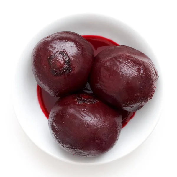 Three whole cooked beetroots in white dish isolated from above. — Stock Photo, Image