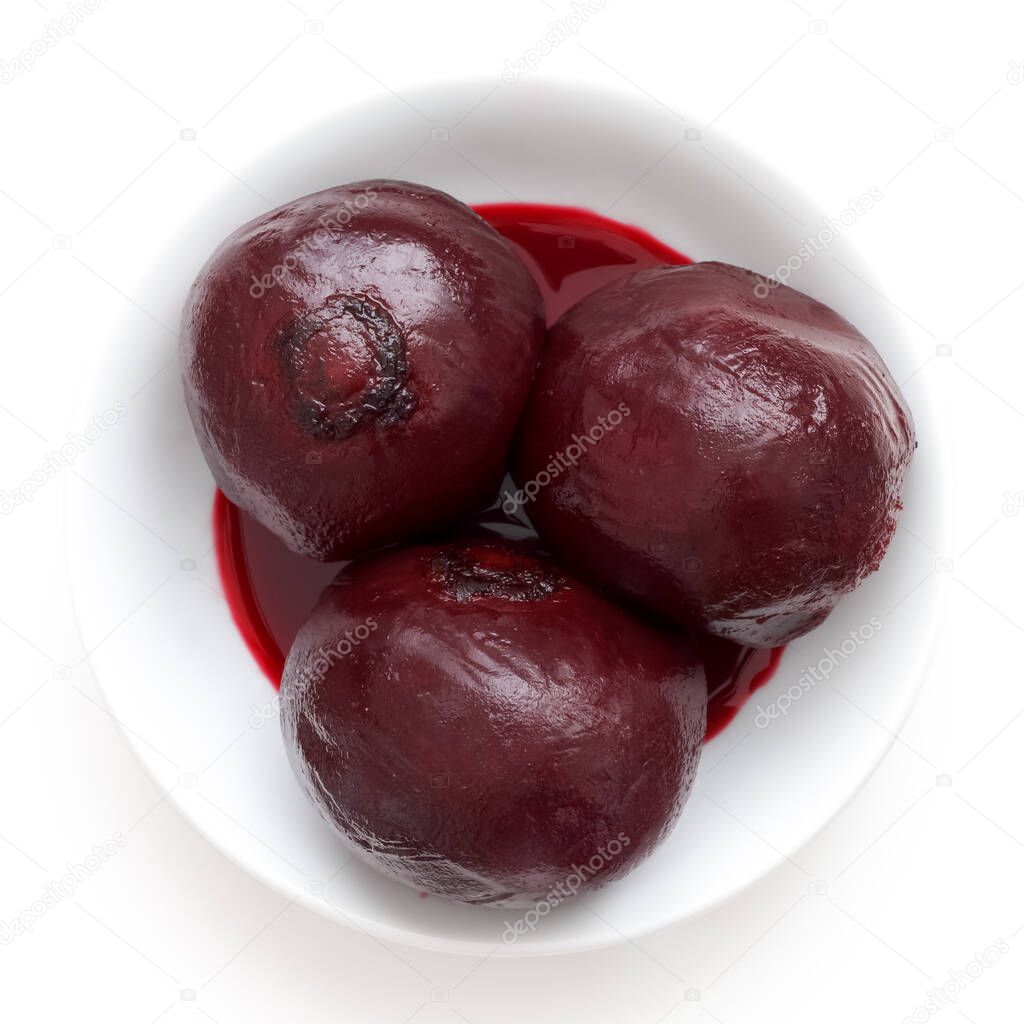 Three whole cooked beetroots in white dish isolated from above.
