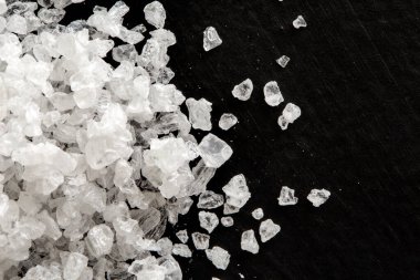 Closeup of coarse salt crystals on black from above. clipart