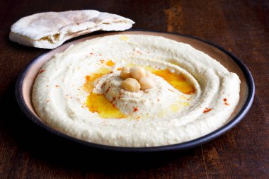 Kahverengi seramik kasede humus ve koyu yalıtılmış pide ekmeği..