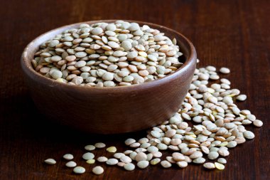 Köy yeşili pişmemiş mercimek kasesi koyu ahşap üzerinde izole edilmiş.