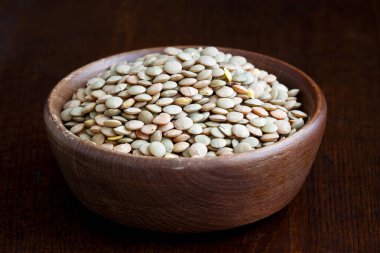 Köy yeşili pişmemiş mercimek kasesi koyu ahşap üzerinde izole edilmiş.