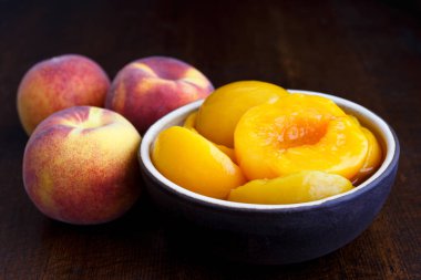 Kavanozda şeftali konservesi. Arka planda koyu renk ve taze. 