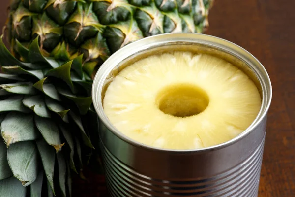 Ananas ringar i tenn på mörkt trä bredvid ananas. — Stockfoto