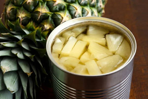 菠萝片，罐装，深色木料，菠萝旁边. — 图库照片