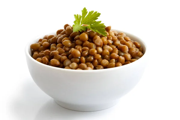 Taça de cerâmica branca de lentilhas marrons cozidas com salsa isolada — Fotografia de Stock