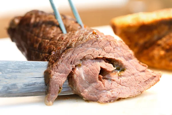 Detail einer Roulade aus gebackenem Fleisch, die mit einem Messer geschnitten wird. — Stockfoto