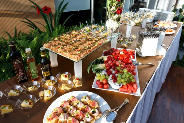 Mesa buffet llena de comida en platos pequeños y un plato de frutas . —  Fotos de Stock