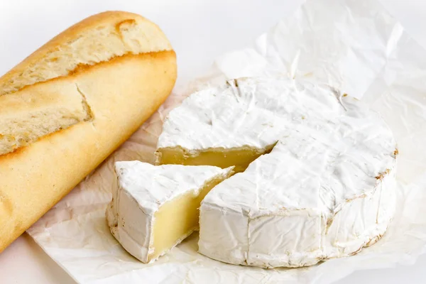 Detail of white mould cheese in wrapping with baguette on white. — Stock Photo, Image