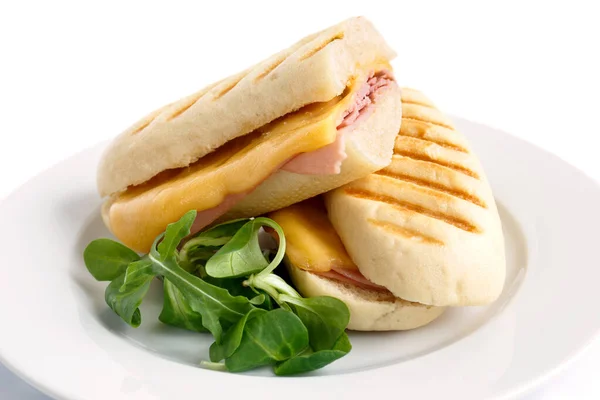 Cut cheese and ham toasted panini melt. On white plate with garn — Stock Photo, Image