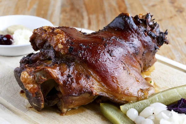 Traditionelle Schweinshaxe auf Holzbrett mit Essiggurken. — Stockfoto