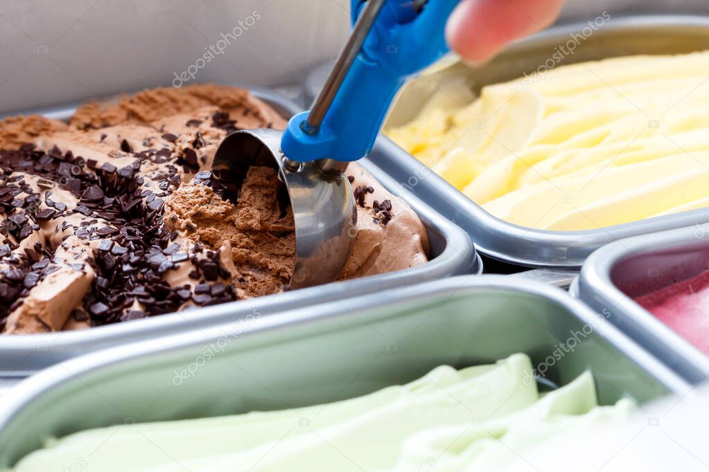 Chocolate chip ice cream being scooped. Surrounded by other flav