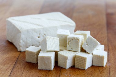 Tahta kesiğinde tofu küpleri olan tek parça beyaz tofu.