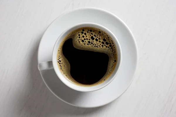 Freshly poured black coffee with froth in white ceramic cup isol — Stock Photo, Image