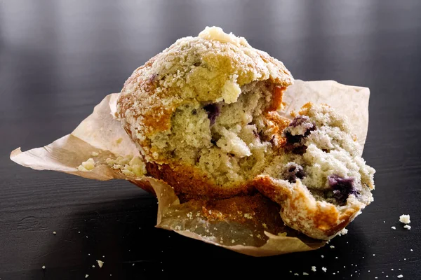 Muffin blueburry cassé sur papier cuisson isolé sur bois noir — Photo