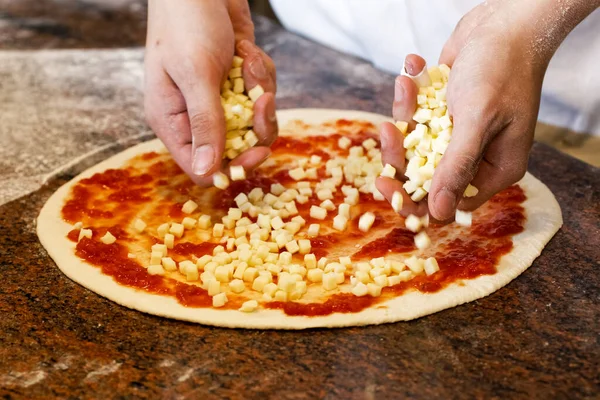厨师的手把莫扎瑞拉奶酪放在西红柿比萨饼上. — 图库照片