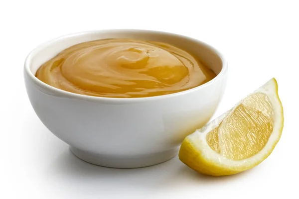 Lemon curd in white ceramic bowl next to lemon wedge isolated on — Stock Photo, Image