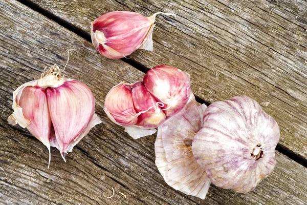 Whole garlic with broken bulb and pink cloves on rustic wooden b — Stock Photo, Image