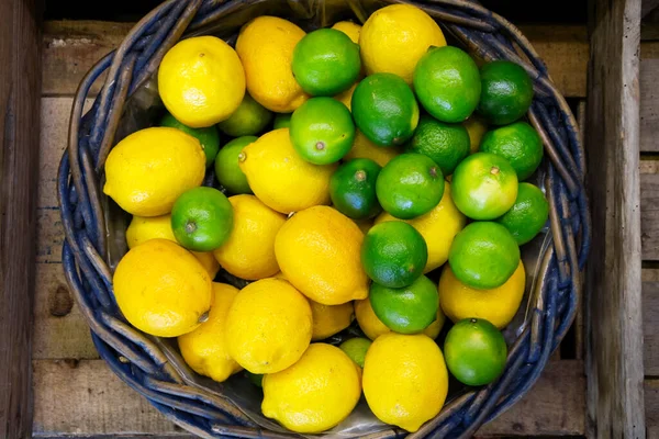 Cesta de mimbre rústica con limones y limas desde arriba . — Foto de Stock