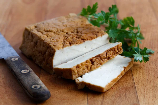 Bloco de tofu defumado, duas fatias de tofu, faca rústica e p fresco — Fotografia de Stock
