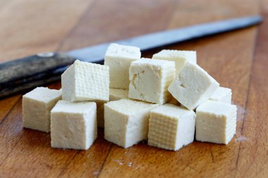 Kesik beyaz tofu küpleri ve odun doğrayan yaban domuzu üzerinde kırsal bıçak.