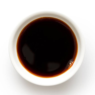 Beyaz seramik kasedeki soya sosu yukarıdan beyaza izole edilmiş..