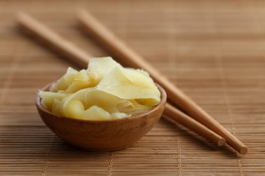 Tahta kasede turşulu zencefil dilimleri bambu hasırının yanında pirzola.