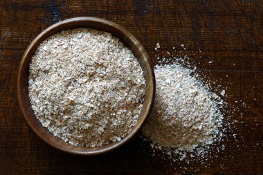 Koyu kahverengi ahşap kaptaki kepekli buğday. 