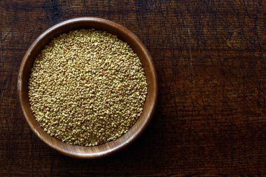 Koyu kahverengi ahşap kabın içindeki yonca tohumları.