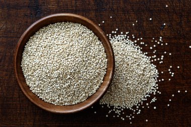 Koyu kahverengi ahşap fro üzerinde izole edilmiş koyu ahşap kasede kinoa tohumları.