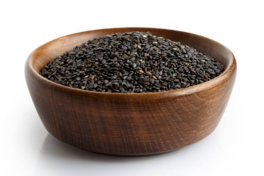 Siyah susam tohumları koyu ahşap kasede, beyazın üzerinde izole edilmiş.. 