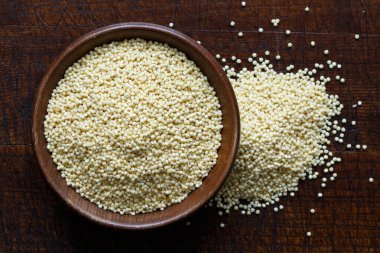 Kahverengi ahşap kasedeki kuru darı yukarıdan izole edilmiş koyu ahşap.