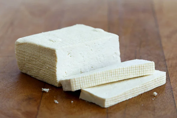 Bloco de tofu branco e duas fatias de tofu em tábua de corte de madeira — Fotografia de Stock