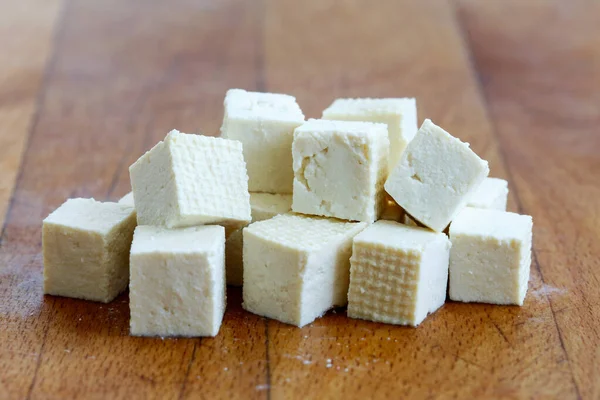 Kostki ciętego białego tofu na drewnianej desce do krojenia. — Zdjęcie stockowe