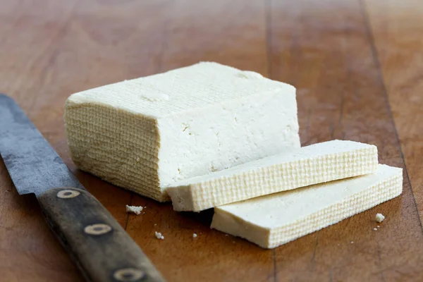 Bloco de tofu branco com duas fatias de tofu e faca rústica no woo — Fotografia de Stock