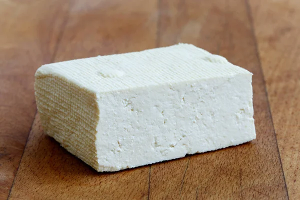 Single block of white tofu on wooden chopping board. — Stock Photo, Image