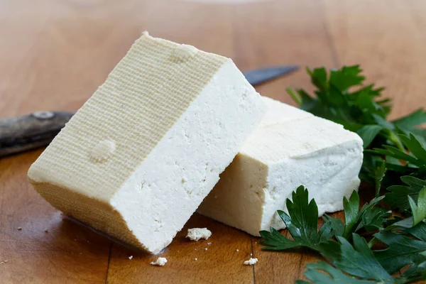 Due blocchi di tofu bianco con prezzemolo fresco e coltello rustico su — Foto Stock