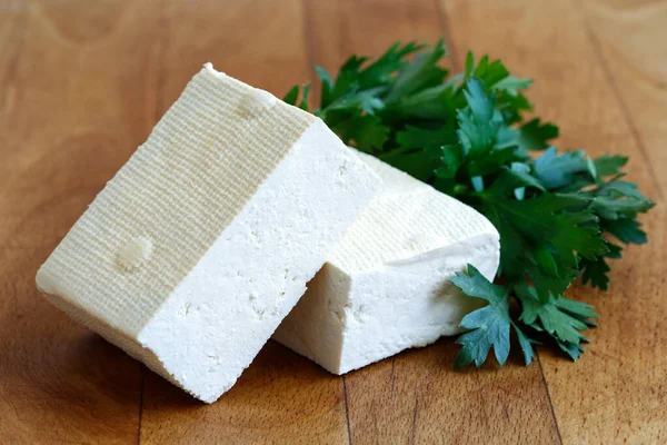 Zwei Blöcke weißer Tofu mit frischer Petersilie auf hölzernen Hackschnitzeln — Stockfoto