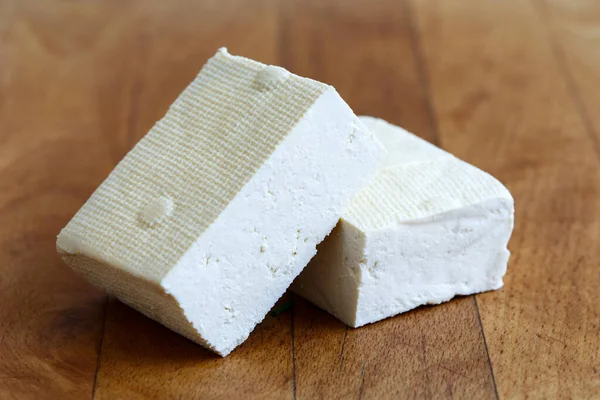 Dwa bloki białego tofu na drewnianej desce do siekania. — Zdjęcie stockowe