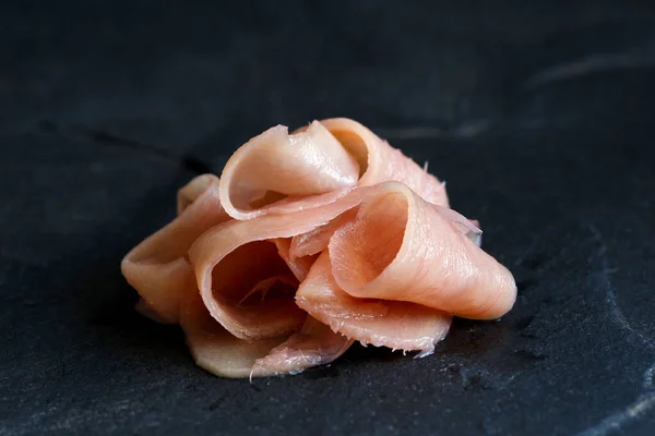 Tas de tranches de gingembre rose mariné isolé sur ardoise noire . — Photo