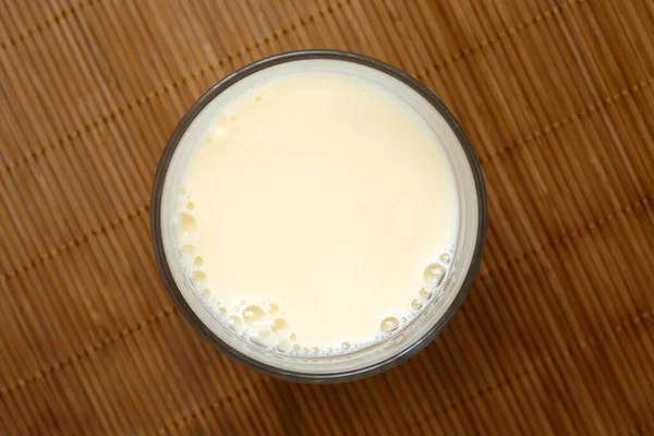 Bicchiere di latte di soia con schiuma su tappetino di bambù dall'alto . — Foto Stock
