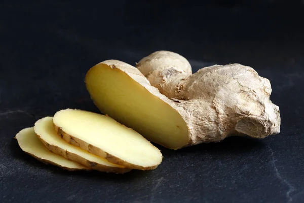 Sliced ginger root isolated on black slate. — Stock Photo, Image