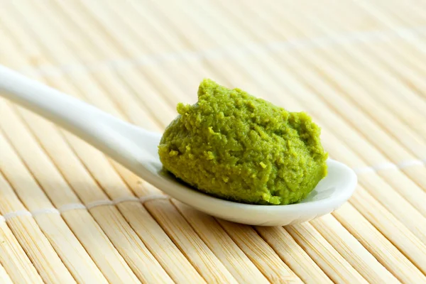 Wasabi pasta en cuchara de cerámica en estera de bambú . — Foto de Stock