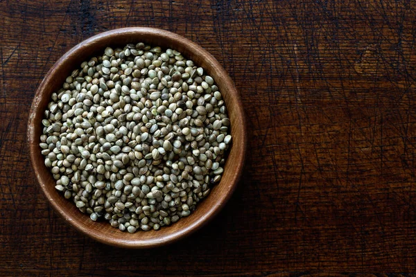 Hemp seeds in dark wooden bowl isolated on dark brown wood from — Stock Photo, Image